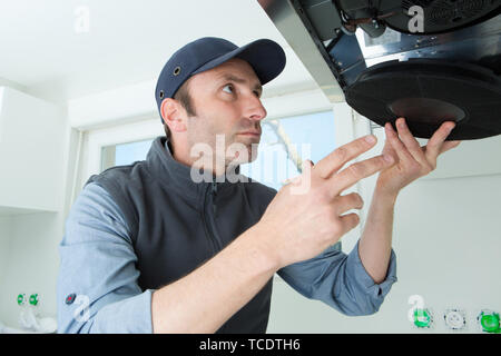 male technician checking kitchen extractor filter with screwdriver Stock Photo