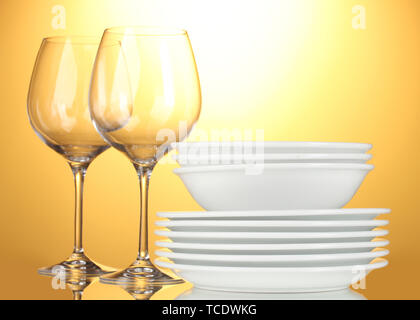 empty bowls, plates, cups and glasses on yellow background Stock Photo