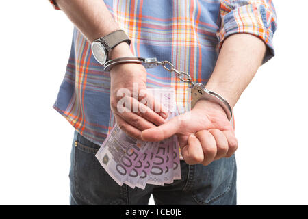 Closeup of corrupted man hiding bribe money behind back and making thumb up gesture with handcuffed hands isolated on white Stock Photo