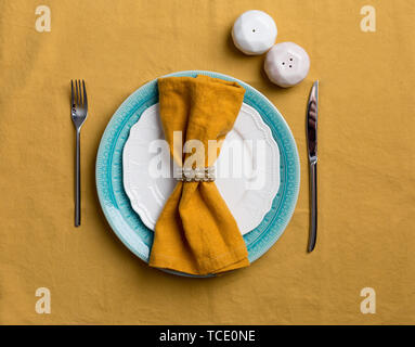 Holiday serving plate with tableware, salt and pepper shaker on orange tablecloth. Flat lay, top view. Concept of holiday table Stock Photo