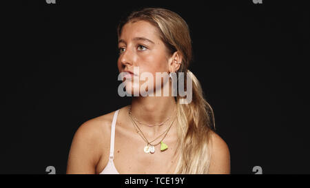 Portrait of a woman in blonde hair isolated on black background. Close up of a woman looking away. Stock Photo