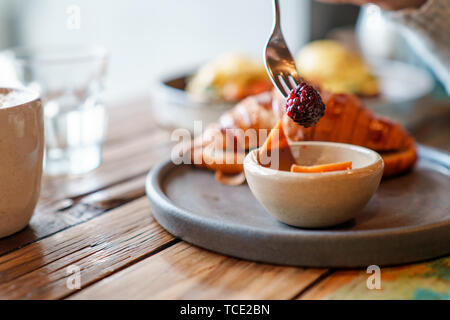 Breakfast croissant with coffee and a person eating blackberry garnish Stock Photo