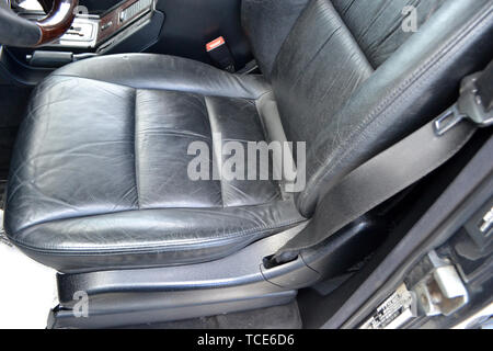 Close-up on the front old classic car seat with black leather trim, of used vehicle in bad condition in the interior after detailing and dry cleaning. Stock Photo