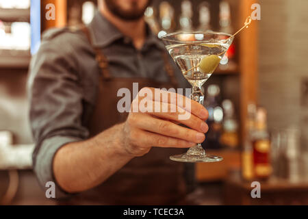 A martini cocktail. Close-up photo of an adult male bar worker holding a martini cocktail in a hand Stock Photo