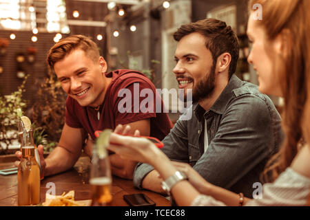 Smiling men. Smiling beaming attractive happy stylish young-adult two men sitting at the bar table Stock Photo