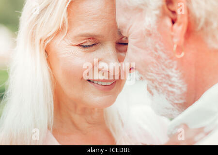 True love. Face of a nice aged woman while hugging her beloved husband Stock Photo