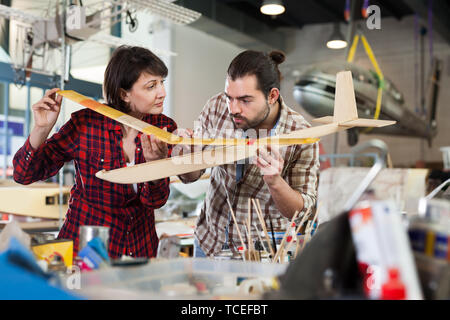 Team of nice aircraft enthusiasts working in workshop on creating of airplane models Stock Photo