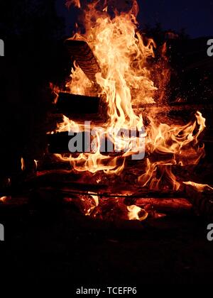 High flames from big bonfire on festival at the nigtht, long trunk inside Stock Photo