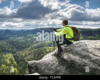 Ultralight runner on trail with tracking poles. Tired sitting tourist with trekking poles in hand. Sunny spring morning in sandstone rocks Stock Photo