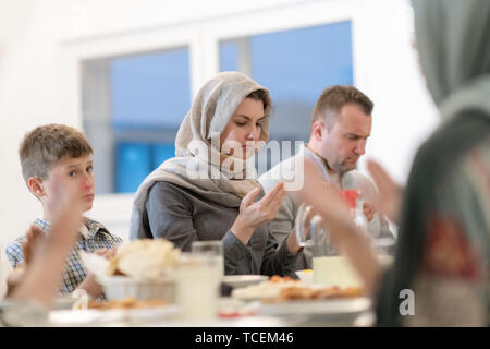 modern muslim family praying before having iftar dinner together during a ramadan feast at home Stock Photo