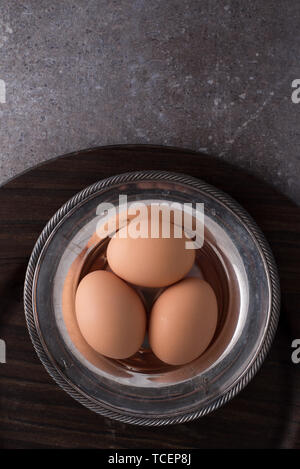 three brown eggs in silver bowl Stock Photo