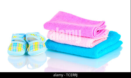 Blue baby booties and three colorful towels isolated on white Stock Photo