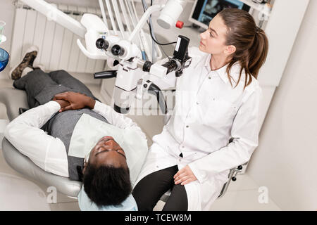 Female dentist advanced user, dental tools. Setup microscope for examining his patients teeth. in dental clinic office. Medicine, dentistry and health Stock Photo