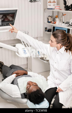 Female dentist advanced user, dental tools. Setup microscope for examining his patients teeth. in dental clinic office. Medicine, dentistry and health Stock Photo