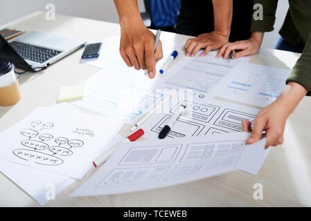 Hands of creative UX and UI designers discussing wireframes of website at meeting Stock Photo