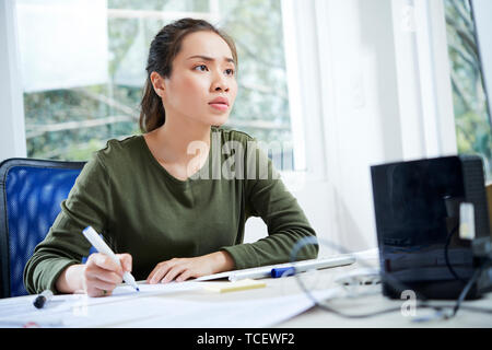 Young Vietnamese UI designer working on website interface at her office table Stock Photo