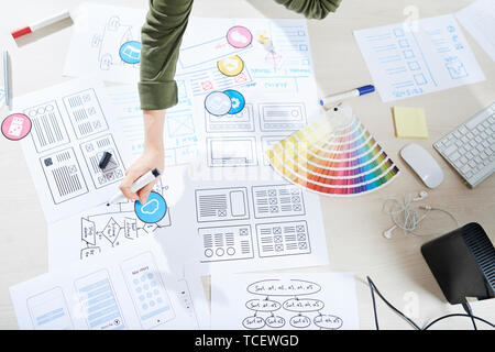 Wireframes of future project, paper samples of icons and color palette on table of UI designer Stock Photo