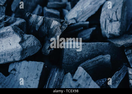 Black coals close up background. Burnt wood texture. Beams in grill, ashes in barbeque top view. Natural smouldering charcoal heap abstract backdrop.  Stock Photo
