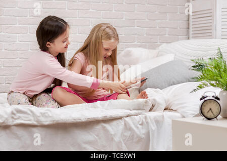 Children quarrel over the tablet. two cute children girls can not share the digital tablet Stock Photo