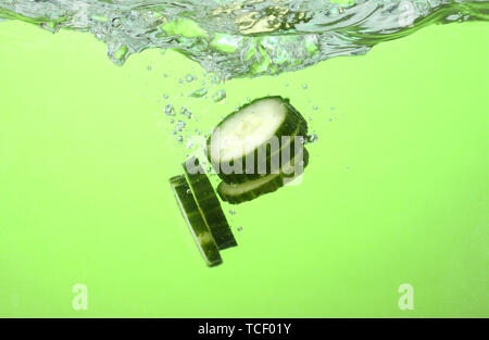 fresh sliced cucumber in water on green background Stock Photo