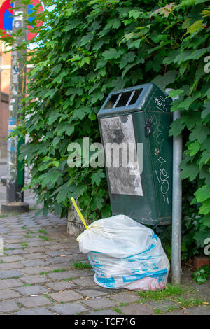 Brussels, Belgium - June 1 2019 : White brussels trash bag next to a green public trash can. Stock Photo