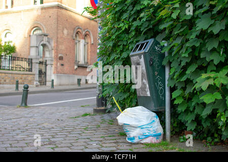 Brussels, Belgium - June 1 2019 : Wide shot of White brussels trash bag next to a green public trash can. Stock Photo