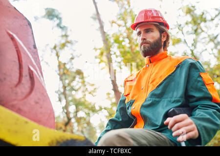 Forest worker as a crane operator on the forwarder while chopping wood or loading Stock Photo