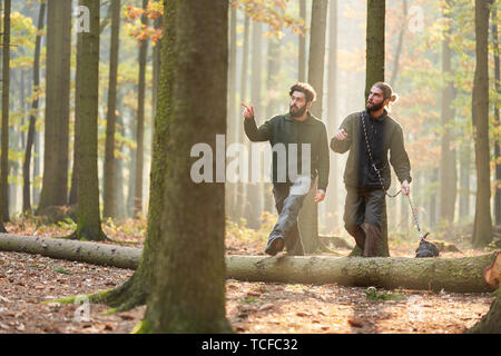Two young foresters at the inspection passage in the forest with a hound as a hunting dog Stock Photo