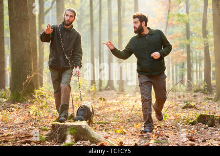 Two hunters with a hound as a sweat dog during the search in the forest Stock Photo