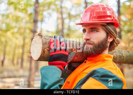 Young forest worker in training while carrying tree trunk in the forest Stock Photo