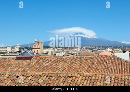 Cityscape of Sicilian Catania in Italy taken from the roof of a building in historical center. In the background there is famous Mount Etna volcano overlooking the beautiful city. Stock Photo