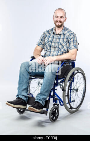 Smiling disabled man sitting in a wheelchair. Positive expression and casual clothes. Stock Photo