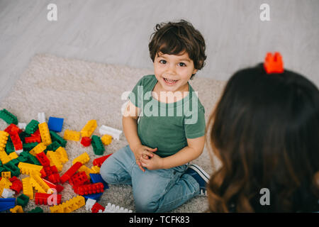 Mother and son playing with lego on carpet in living room Stock Photo