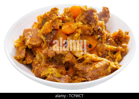 Stewed pork with braised cabbage and carrot served on plate. Isolated over white background Stock Photo