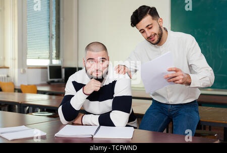 Young guy sitting at classroom worried because of difficulties with studies Stock Photo