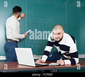 Two male university students preparing for exams together at classroom Stock Photo