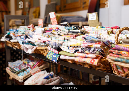 View of cloth rolls of different colors and patterns on shelves in fabric store Stock Photo