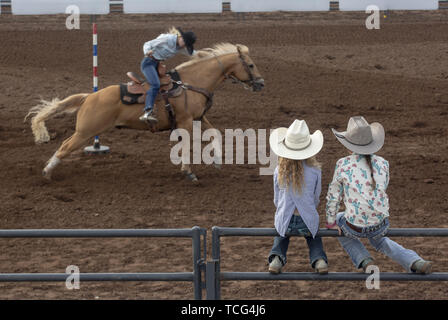 Heber City, Utah, USA. 7th June, 2019. Little girls sit on a fence to watch a pole bending event at the Utah High School Rodeo Association Finals in Heber City Utah, June 7, 2019. Students from across the state of Utah gathered to compete in Barrel Racing, Pole Bending, Goat Tying, Breakaway Roping, Cow Cutting, Bull Riding, Bareback Riding, Saddle Bronc Riding, Tie Down Roping, Steer Wrestling, and Team Roping. Credit: Natalie Behring/ZUMA Wire/Alamy Live News Stock Photo