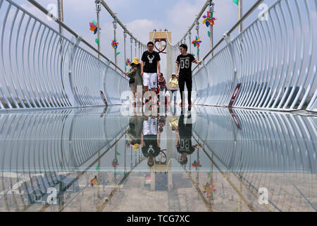 Nantong, China. 8th June, 2019. Tourists walk on a glass-bottomed bridge at a scenic area of Nantong, east China, June 8, 2019. Credit: Xu Congjun/Xinhua/Alamy Live News Stock Photo