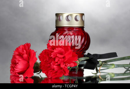 Memory lantern with candle,  carnations and black ribbon on grey background Stock Photo