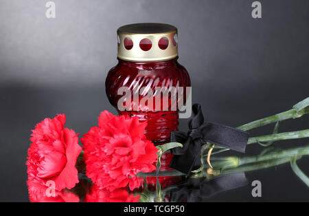 Memory lantern with candle,  carnations and black ribbon on grey background Stock Photo