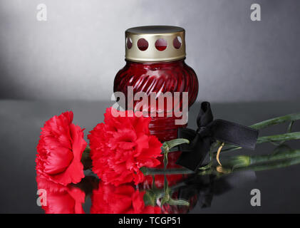 Memory lantern with candle,  carnations and black ribbon on grey background Stock Photo