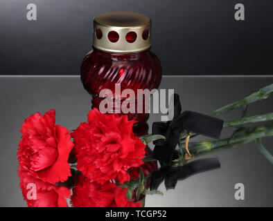 Memory lantern with candle,  carnations and black ribbon on grey background Stock Photo