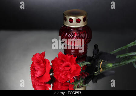 Memory lantern with candle,  carnations and black ribbon on grey background Stock Photo