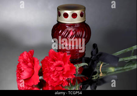 Memory lantern with candle,  carnations and black ribbon on grey background Stock Photo