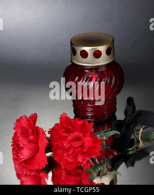 Memory lantern with candle,  carnations and black ribbon on grey background Stock Photo