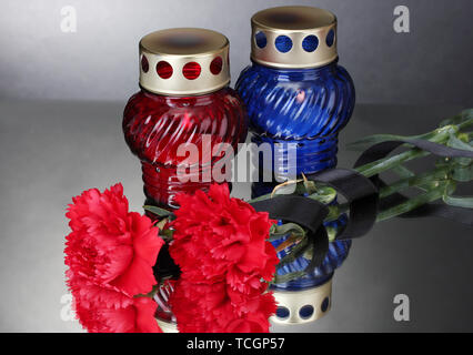 Memory lanterns with candles,  carnations and black ribbon on grey background Stock Photo