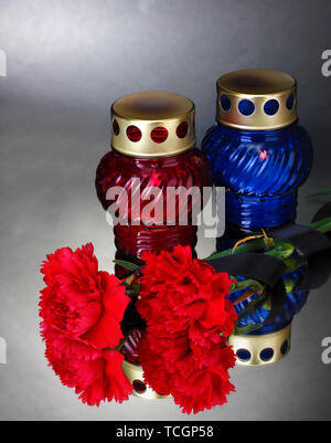 Memory lanterns with candles,  carnations and black ribbon on grey background Stock Photo