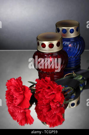 Memory lanterns with candles,  carnations and black ribbon on grey background Stock Photo