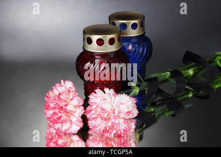 Memory lanterns with candles,  carnations and black ribbon on grey background Stock Photo